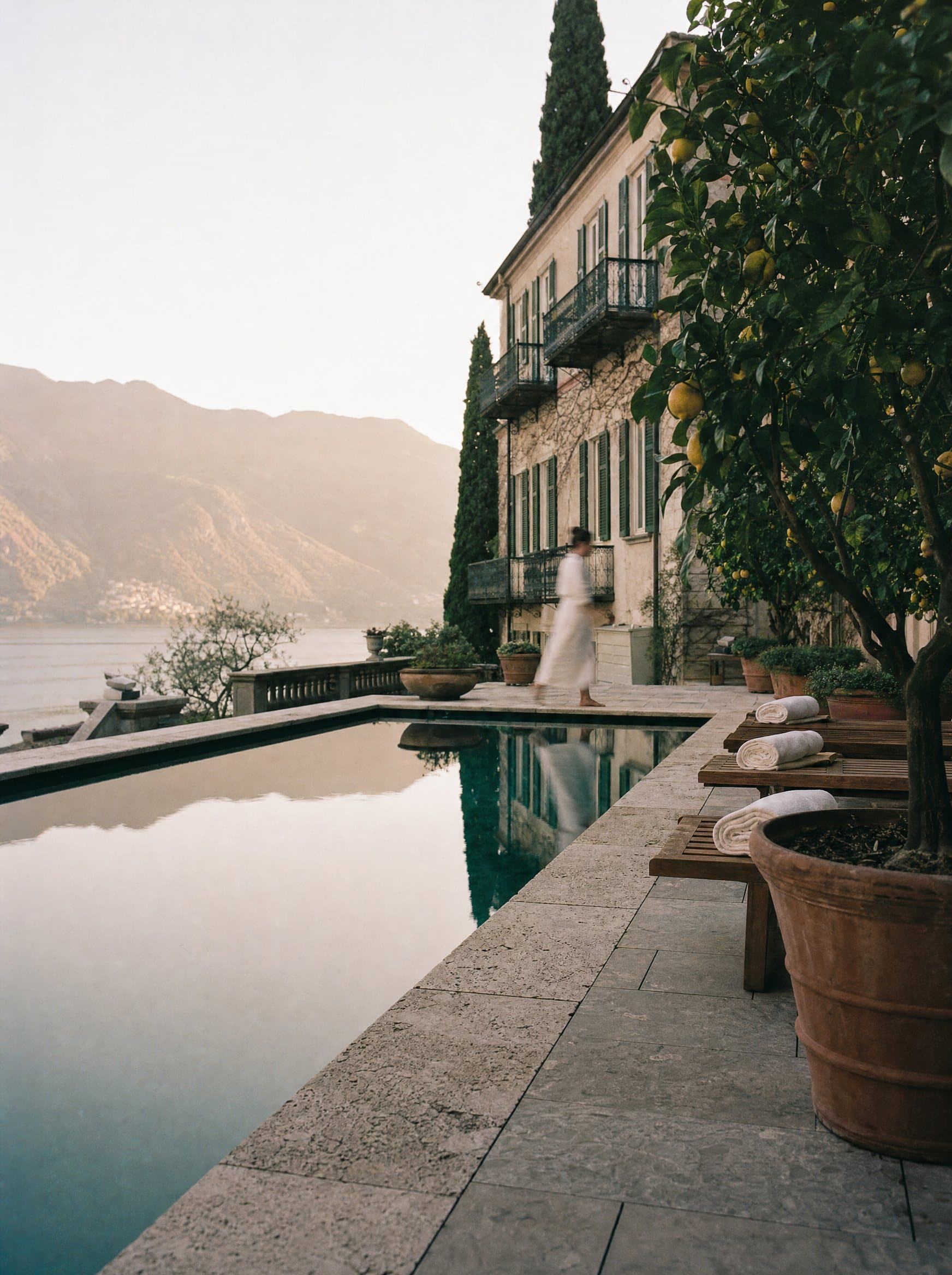 A hotel pool terrace on Lake Como, a guest in a robe blurred in motion